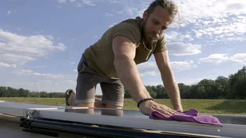 Man wiping a solar panel on top of a caravan Video stock 225905701