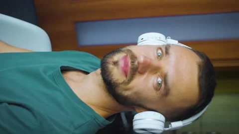 Man in wireless headphones listening to music, dancing, turns head and looking Stock Footage 166310576