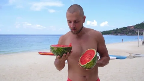 Man without clothes with a big juicy ripe watermelon in hands on a background of Stock Footage