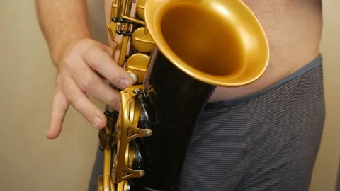 A Man Without Clothes Playing An Old Saxophone Stock Footage 153370050
