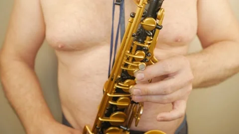 A Man Without Clothes Playing An Old Saxophone Stock Footage 153370052