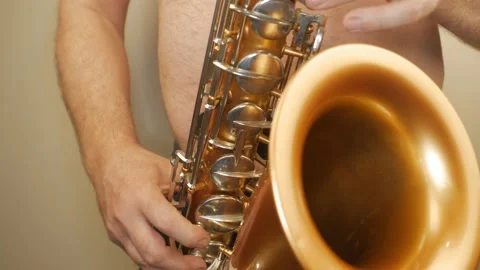 A Man Without Clothes Playing An Old Saxophone Stock Footage 153370060