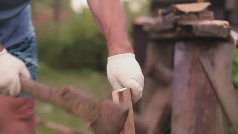 A man without a face in the yard splits boards with an ax 库存影片 137975410