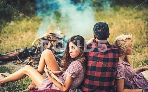Man with women at bonfire. Boyfriend and girlfriends read books. Friends enjoy Stock Photos