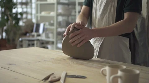 Man on wooden table in workshop kneads clay mass for ceramics. Stock Footage 90130172