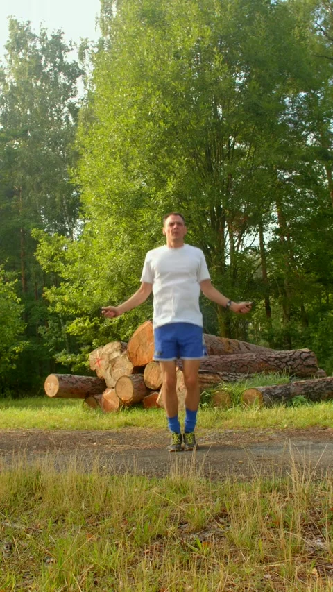 A man in the woods interacts with logs and jumps rope, blending peace Stock Footage 314346159