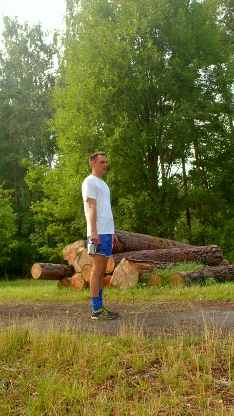 A man in the woods interacts with logs and jumps rope, blending peace Vídeos de archivo 316490014