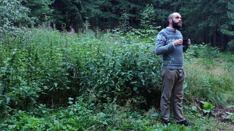 Man in wool sweater drinking coffee in forest Stock Footage 344893549