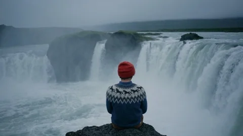 Man in wool sweater on edge of waterfall rock Stock Footage 117414809