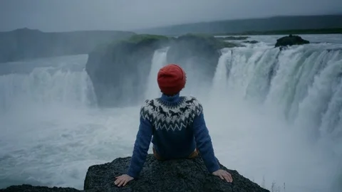 Man in wool sweater on edge of waterfall rock Stock Footage 117415436