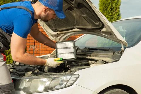 Man in work clothes changes car engine air filter outdoors Stock Photos