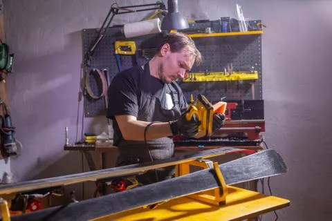 A man in work clothes repairman in the workshop ski service repairing the ski Stock Photos
