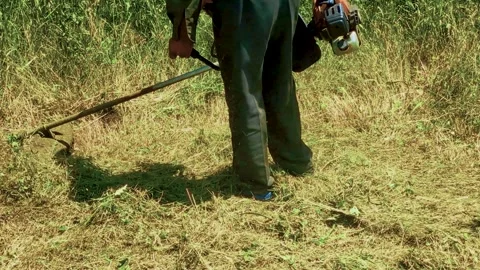 A man in work clothes uses a trimmer Stock Footage 310939887