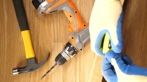 Man with work glove using ba tape measure against a plank of wood Stock Footage 90764827