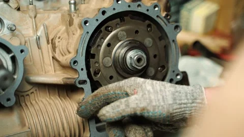 A man in work gloves installs a gasket between the engine and the gearbox Vidéo 159984232
