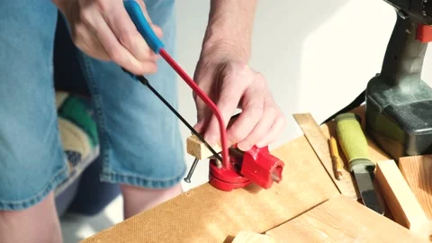 A man in work gloves is sawing a small block of wood with a hand saw. DIY. Stock Footage 151874943