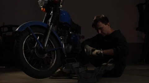 Man in work gloves squatting on the floor, opening a metal toolbox beside a Stock Footage 342771063