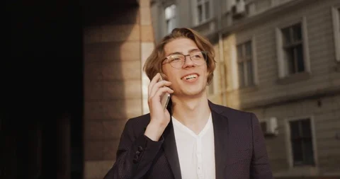 Man at work. Handsome young man with long hair talks on the phone walking around Stock Footage 95881977
