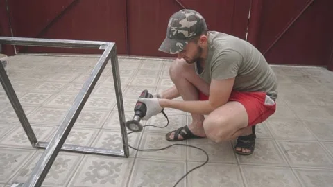 A man at work holds a drill with an iron nozzle Vidéo 145182317