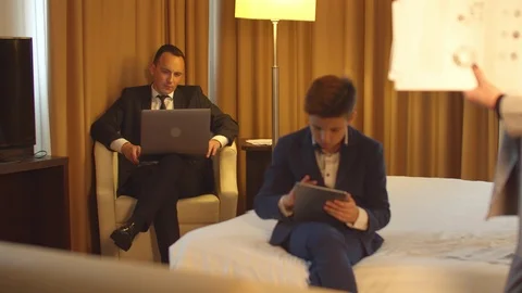 Man in work on laptop, little boy sit with tablet,woman look on documents in Stock Footage 121940751