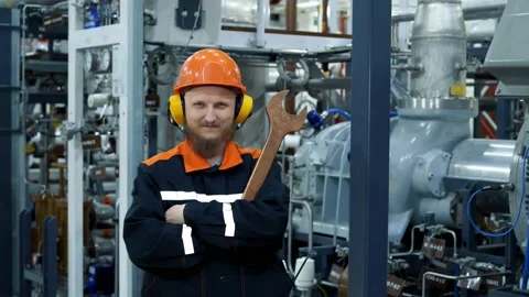 A man at work in an orange helmet and headphones holds a wrench near the gas Stock Footage 168002128