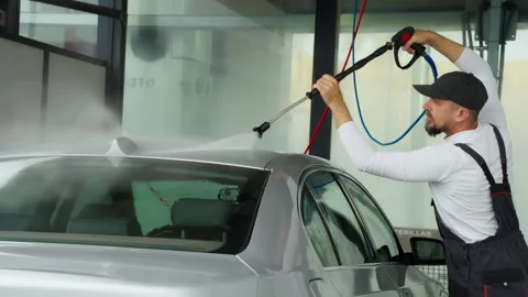 Man in work outfit wash car at self-service car wash station. Man rinsing r.. Stock Footage 320890981
