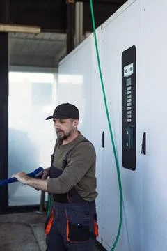 Man in work overalls and cap performing a cleaning job at a contemporary ca.. Stock Photos