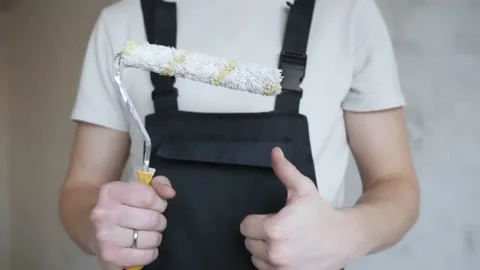 A man in work overalls shows a paint roller to the camera. Stock Footage 144569699