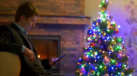 The man work with phone touchscreen by fireplace and tree New Year background Stock-Footage 47164258