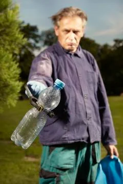 Man at work pick up garbage on grass in park Foto stock