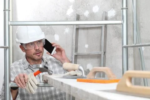 Man work, professional construction worker  with mobile cell phone, plasterin Stock-Fotos