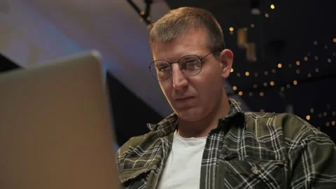 Man work remotely using laptop sitting at couch in home interior.Serious Guy Stock Footage 225655053