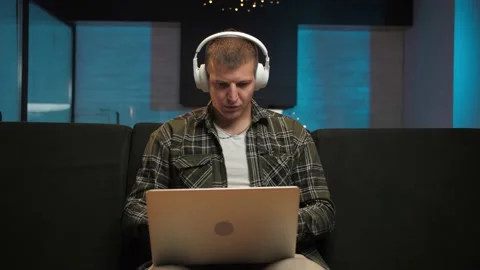 Man work remotely using laptop sitting at couch in home interior.Serious Guy Stock Footage 225655210