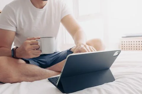 Man work with tablet and coffee in bedroom. Concept of work from home. Фото