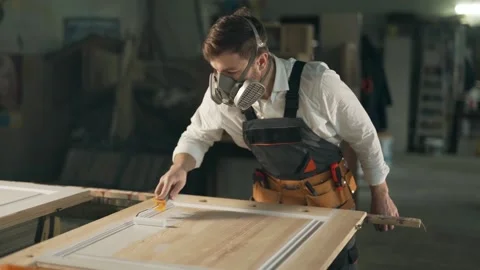 Man in work uniform and respirators paints a wooden product with a roller Stock Footage 149266649