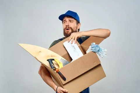 Man in work uniform with box in hands tools lifestyle light background Fotos Stock