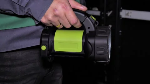 A man in a work uniform illuminates himself with a flashlight in a dark room Stock Footage 222966087