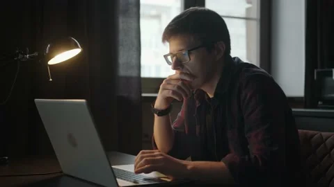 Man at work: a young man in front of a laptop in a dark room. Stock Footage 162755869