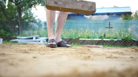 Man worker align wooden plank and tamp sand with gravel Stock Footage 99740747