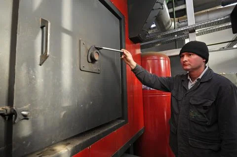 Man worker checking steam generation vessel working, modern city boiler house Stock Photos