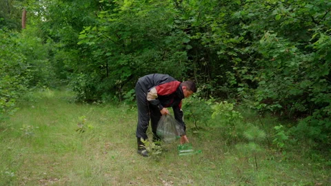 Man worker cleaner remove garbage rubbish in forest at meadow Stock Footage 158124417