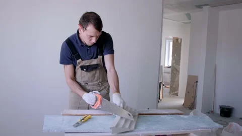 Man worker cuts cornice plaster fretwork with metal saw Stock Footage 151784447
