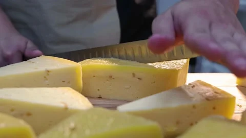 Man worker cutting off triangle pieces of cheese with a knife on the desk Stock Footage 160079278