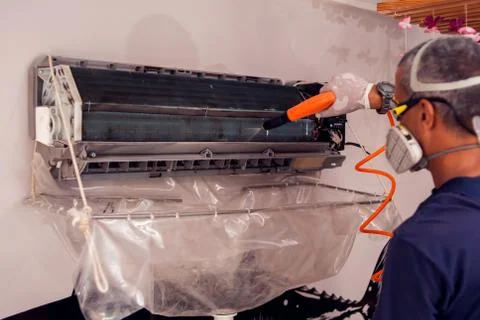 Man worker doing professional cleaning of air conditioning. Stock Photos