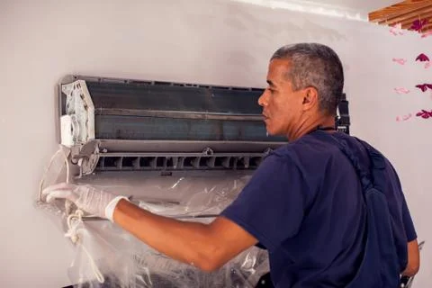 Man worker doing professional cleaning of air conditioning. Stock Photos