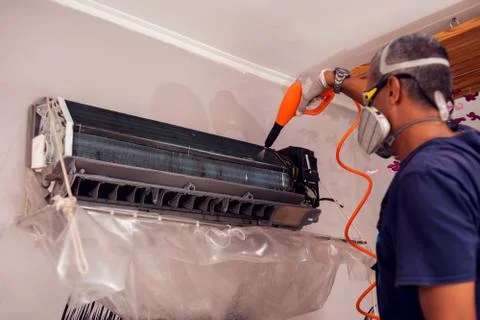 Man worker doing professional cleaning of air conditioning. Stock Photos