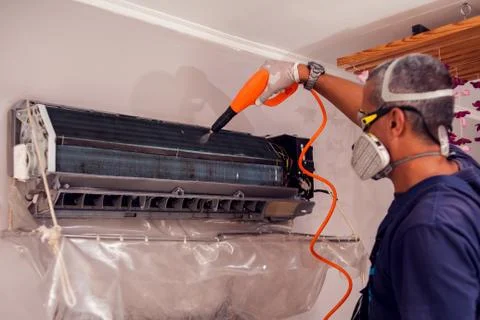 Man worker doing professional cleaning of air conditioning. Stock Photos