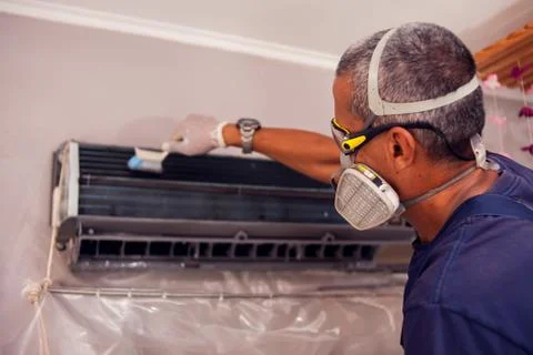 Man worker doing professional cleaning of air conditioning. Stock Photos