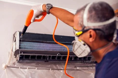 Man worker doing professional cleaning of air conditioning. Stock Photos