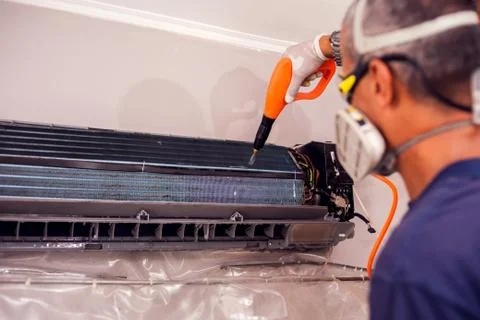 Man worker doing professional cleaning of air conditioning. Stock Photos